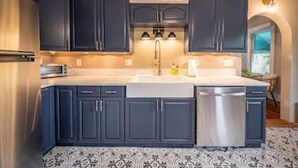 Una cucina con mobili scuri, una lavastoviglie in acciaio inox e un pavimento decorato.