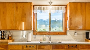 Eine Küche mit Holzausstattung, einem Spülbecken und einem Fenster mit Bergblick.