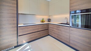 Una cocina moderna con armarios de madera, un lavamanos de acero inoxidable y un horno empotrado.