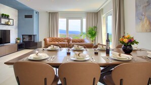 Comedor con una mesa preparada para cuatro personas, un sofá de cuero, un televisor y una vista panorámica.