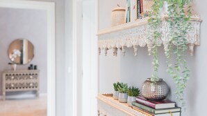 Un pasillo con un estante blanco decorativo que sostiene libros, una pequeña planta en maceta y un cuenco decorativo.