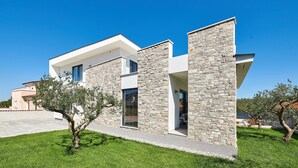 Ein modernes, zweistöckiges Haus mit Naturstein-Fassade und großen Fenstern.