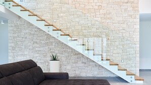 Ein modernes Interieur mit einer Steinwand, einer Glastreppe und einem dunkelbraunen Ecksofa.