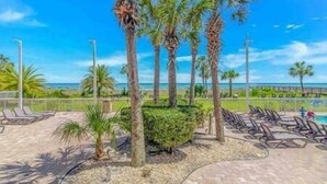 A paved area with palm trees, a pool, and lounge chairs. - Oceanfront Studio • Indoor Waterparks • Dunes Village Resort (Myrtle Beach)