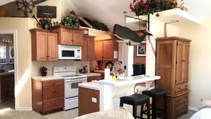 A kitchen with wooden cabinets, a white countertop, and a hanging light fixture. - OCTOPUS SUITE, fire pit, BBQ, wildlife viewing platform, shared oceanfront deck. (Brookings)