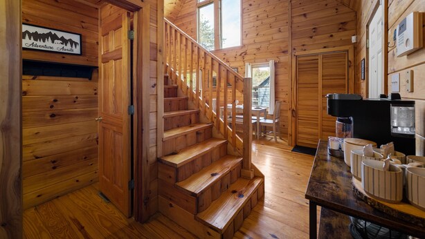 Ein Holzblockhaus-Interieur mit einer Treppe, die zu einem Essbereich führt.