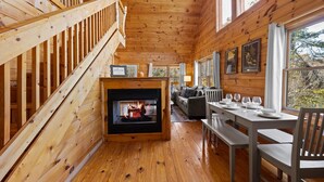 Ein Holzblockbau-Innenraum mit Kamin, Essbereich und einer Treppe.