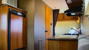 Una kitchenette compacta con gabinetes de madera, una encimera y una estufa.