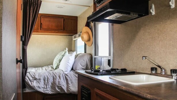 Una kitchenette funcional con fregadero, estufa y armarios.