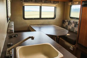 Compact kitchenette with sink, countertop, and window offering a view of the surrounding landscape.