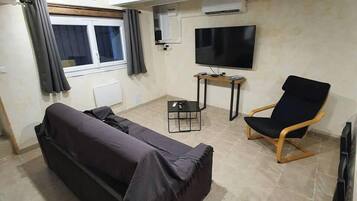A living room with a sofa, a chair, a TV, and a small table.