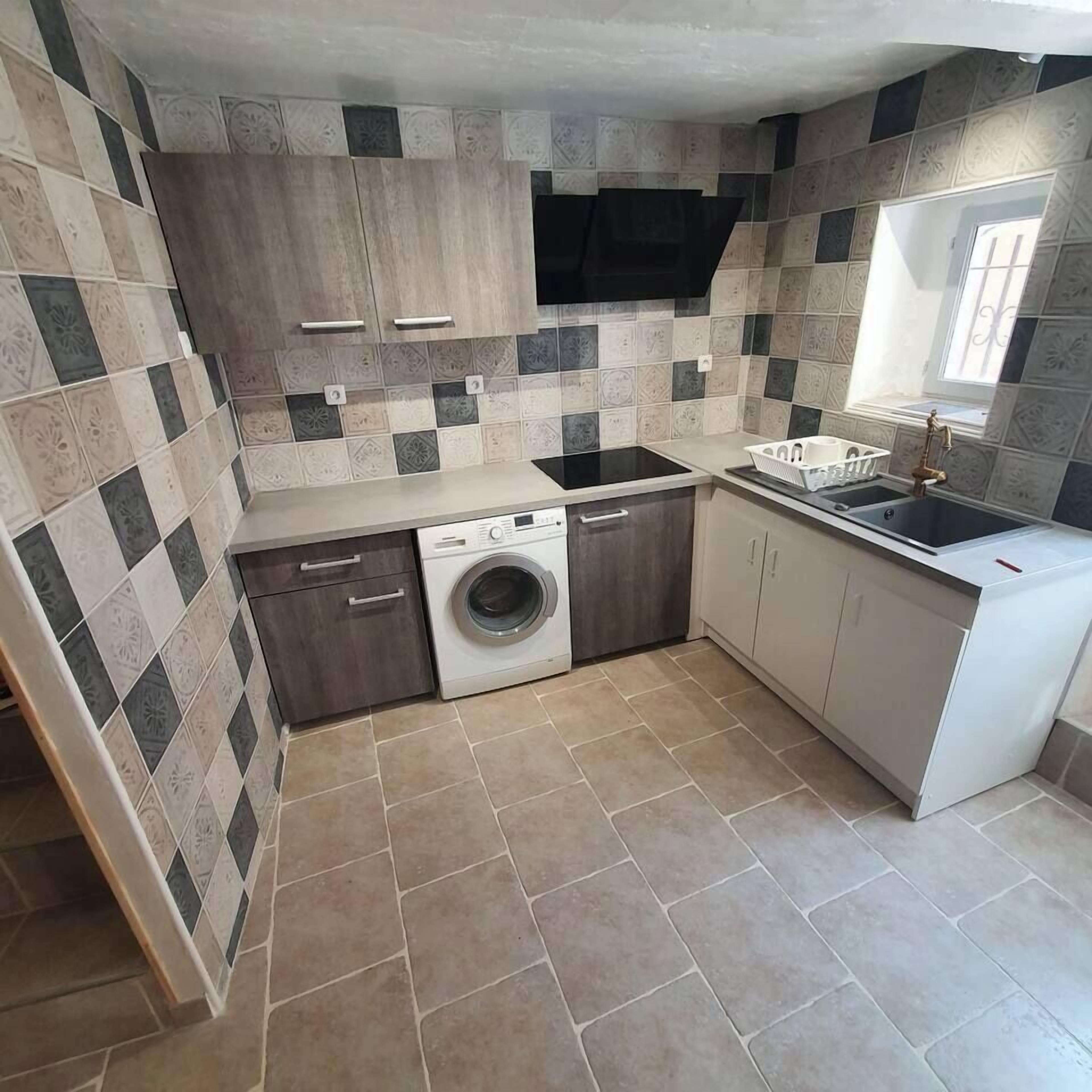 A compact kitchen with a washing machine, a sink, and a window.