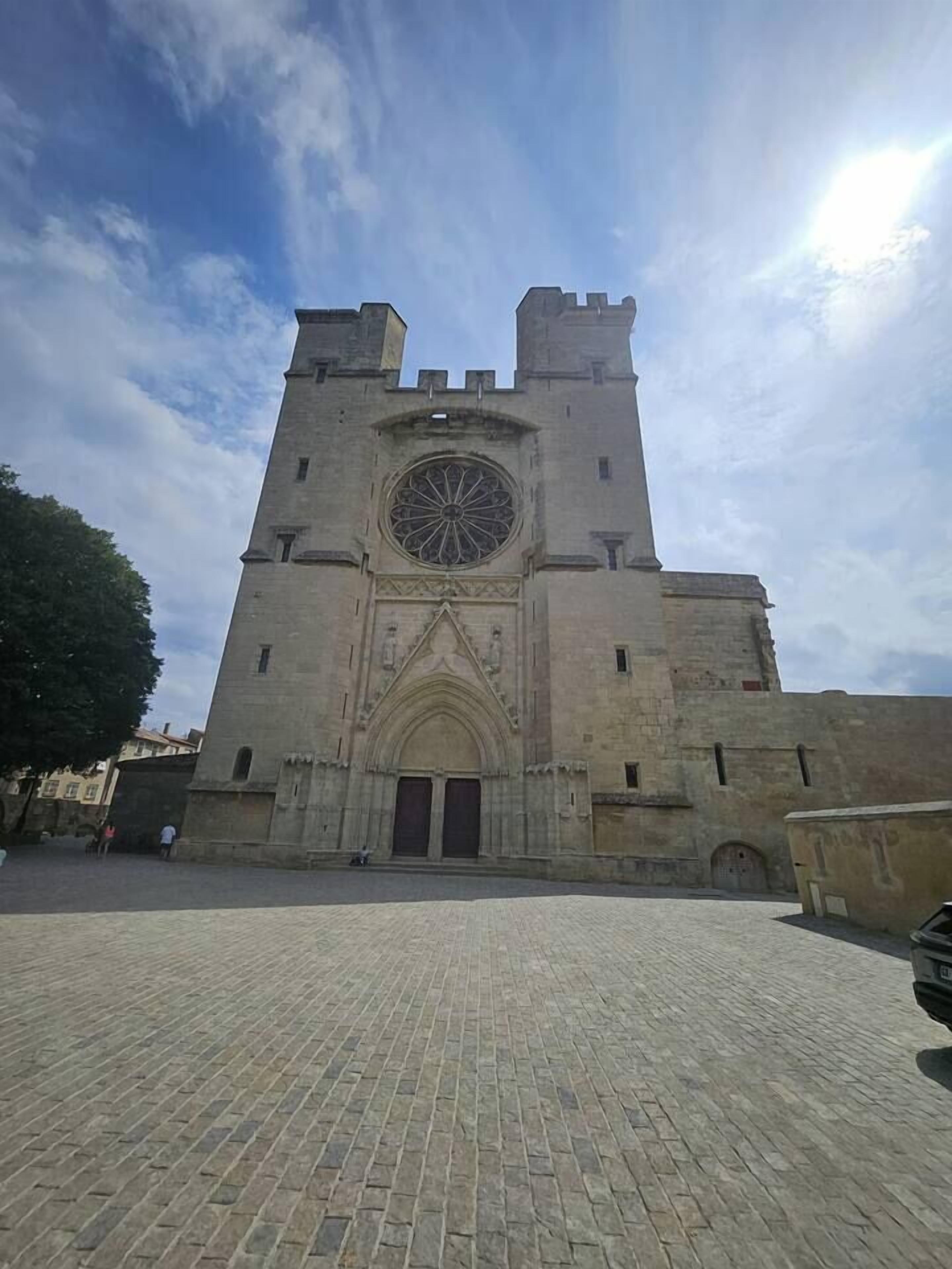 A historic stone building with a large circular window and two symmetrical towers.