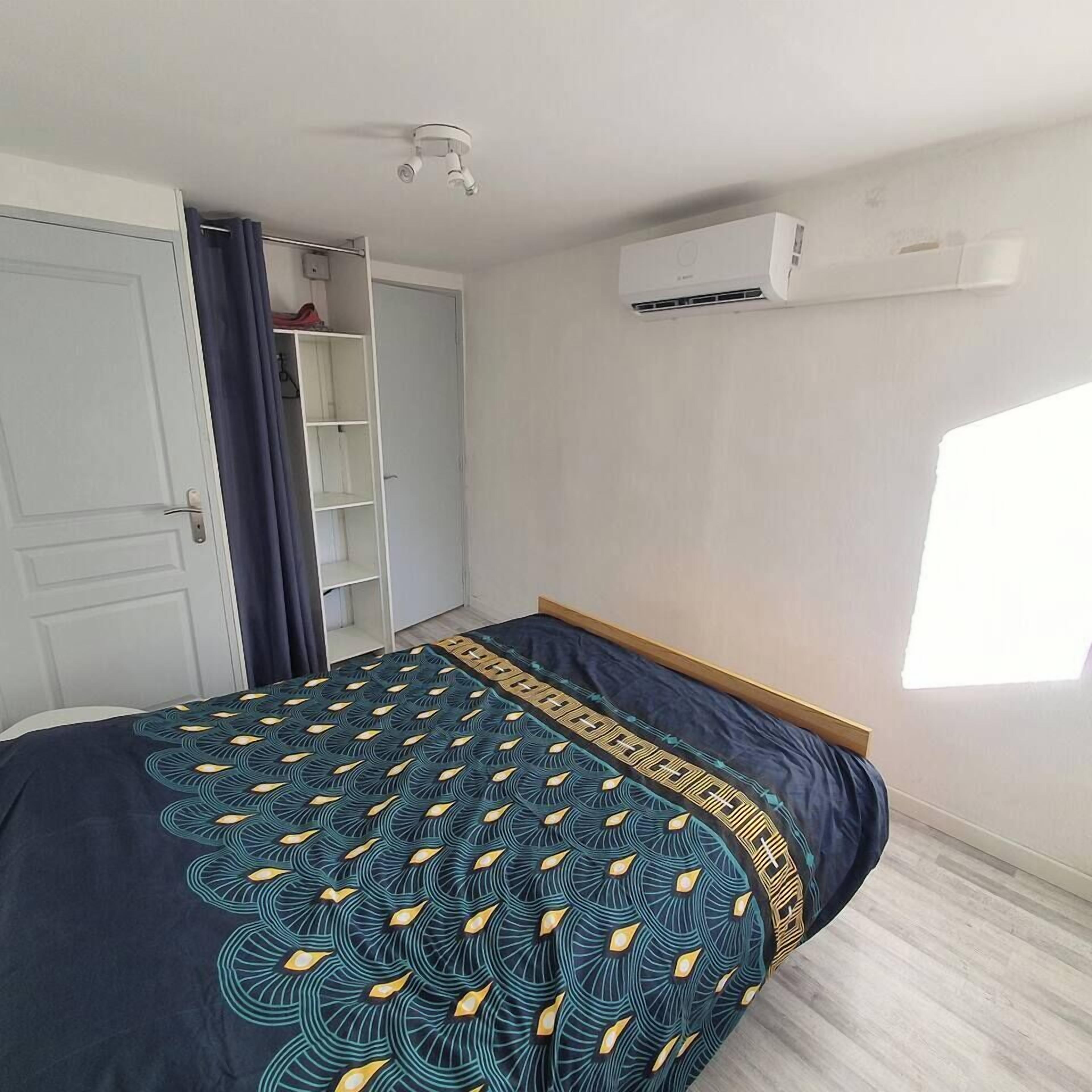 A bedroom with a bed, a wardrobe, a ceiling fan, and an air conditioning unit.