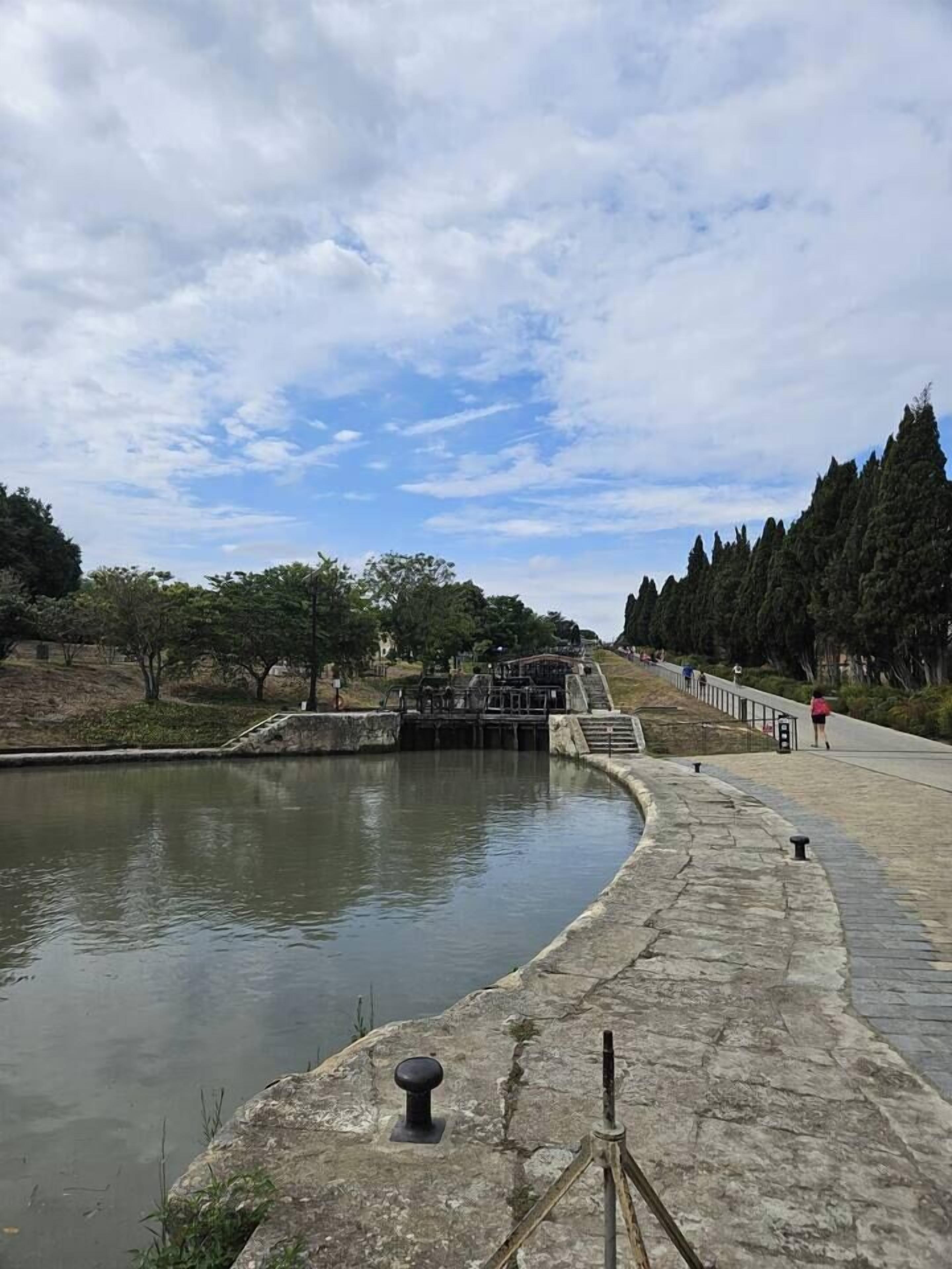 A calm water body with a stone pathway and steps leading to a small bridge.