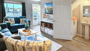 Ein Wohnzimmer mit einer Couch, einem Couchtisch und einem an der Wand befestigten Fernseher.