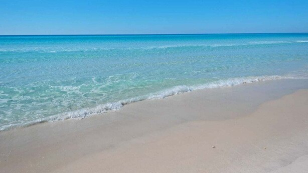 Ein Strand mit klarem türkisblauem Wasser und einem sandigen Ufer.