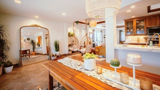 A spacious living area with a wooden floor, a dining table set with candles, and a large hanging light fixture. - Luxury Joshua Tree Retreat w/ Hot Tub, BBQ and Games (Joshua Tree)