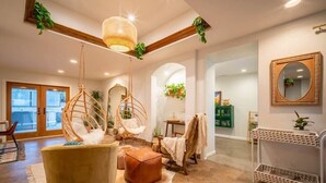 A modern living room with a hanging chair, a sofa, and a small table. - Luxury Joshua Tree Retreat w/ Hot Tub, BBQ and Games (Joshua Tree)