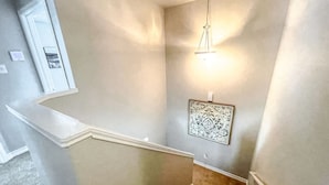 Eine Treppe mit weißer Handlauf, einer Lampe und einem gerahmten Kunstwerk an der Wand.