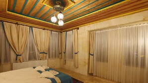 A hotel room with a bed, curtains, a radiator, and a ceiling with wooden beams and a chandelier.