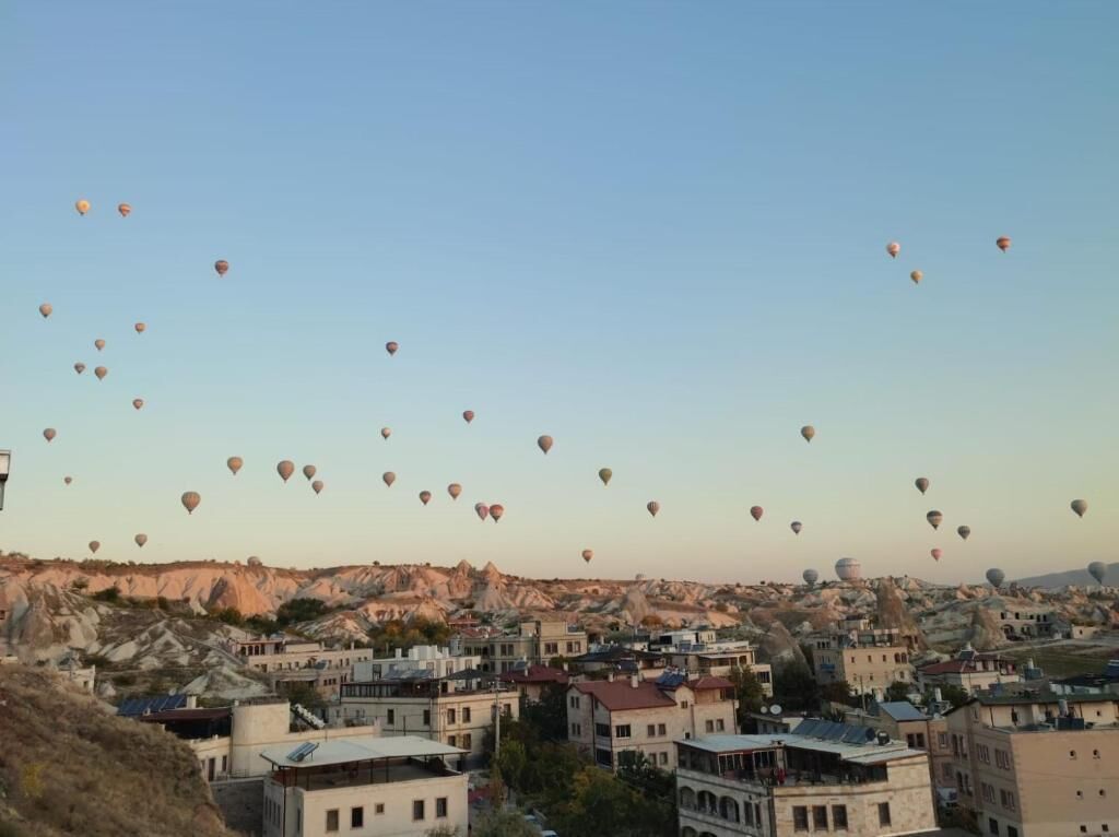 A town with numerous hot air balloons in the sky.