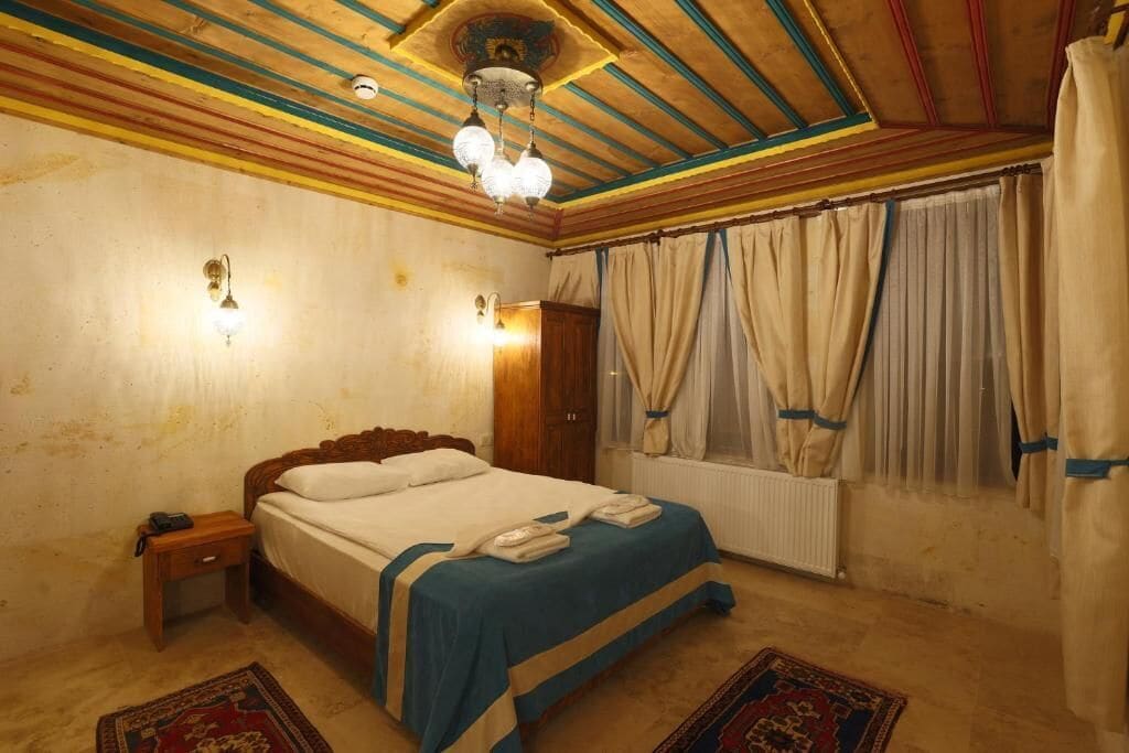 A bedroom with a wooden bed, a nightstand, a radiator, and curtains.