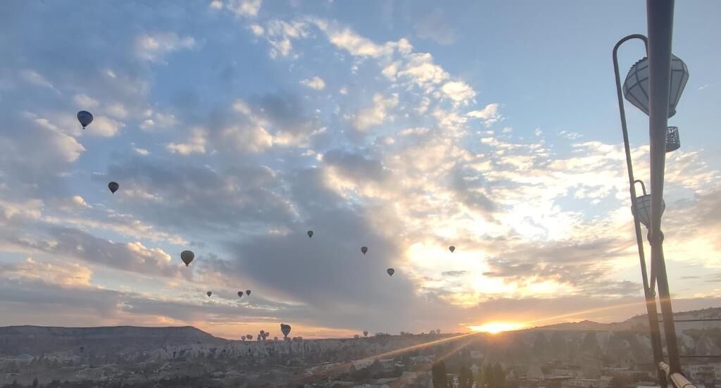 A sunset with hot air balloons in the sky over a cityscape.