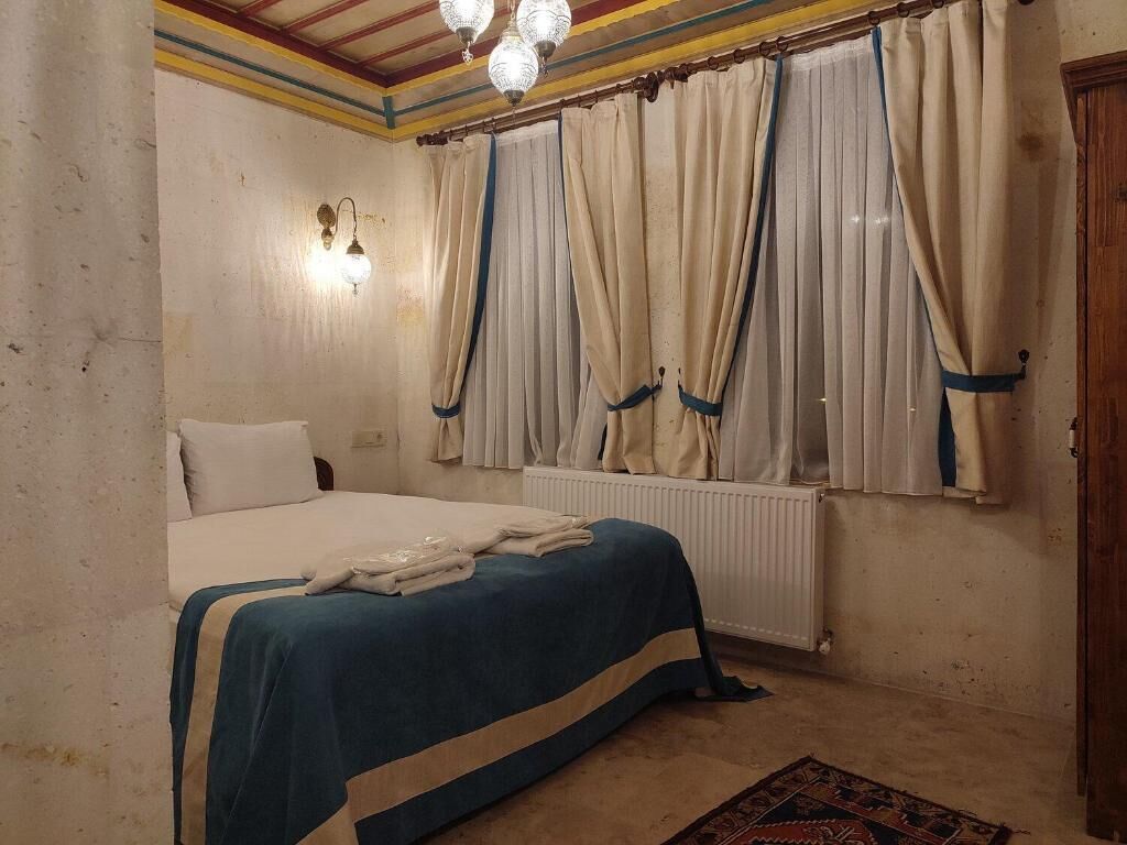 Une chambre à coucher avec un lit, des rideaux, un radiateur et un tapis à motifs.