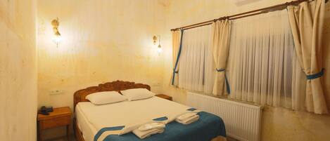 A bedroom with a wooden bed, a nightstand, a radiator, and a window with curtains.