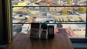 A view through a window with hot air balloons in the sky, a cityscape, and a table with items on it.