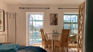 Ein Schlafzimmer mit Bett, Fenster, Balkon mit Stühlen und Blick ins Freie.