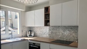 A modern kitchen with white cabinets, a built-in oven, a coffee maker, and a window with a view of the outside.