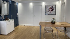 A modern kitchen with a wooden table, clear glass chairs, and a white cabinet.
