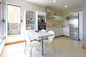 Uma cozinha moderna com armários brancos, forno embutido e geladeira de aço inoxidável.