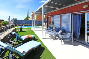 A covered outdoor area with a pool, lounge chairs, and a patio table. - Salobre Vista Golf 5 (San Bartolomé de Tirajana)