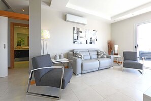 Uma sala de estar moderna com um sofá cinza, duas poltronas cinzas, uma mesinha e um abajur.
