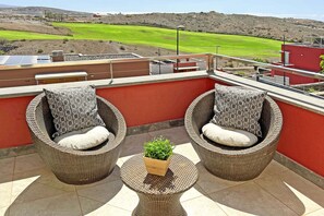 A balcony with wicker chairs, a small table, and a potted plant. - Salobre Vista Golf 5 (San Bartolomé de Tirajana)