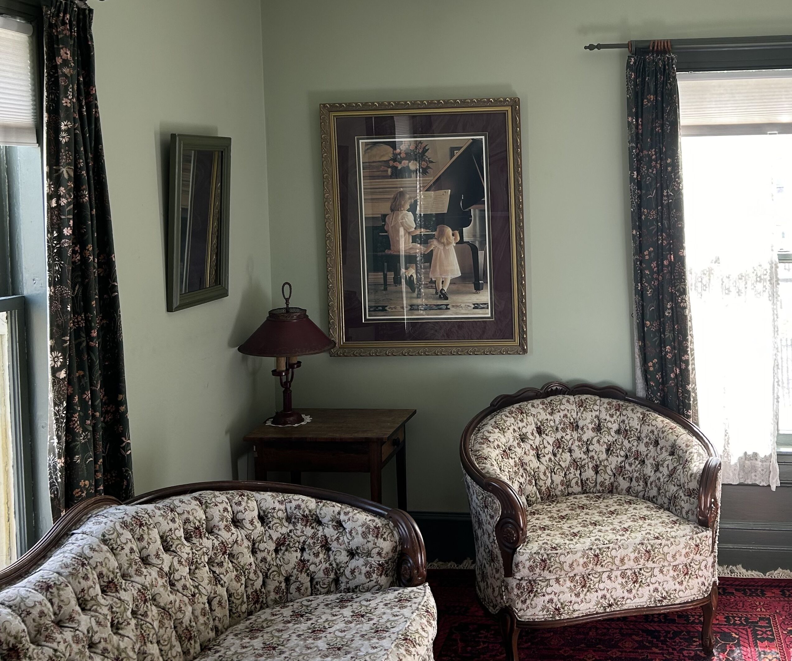 A room with two upholstered armchairs, a small table with a lamp, and a framed picture on the wall.