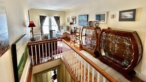 A spacious living room with a high ceiling, a staircase, and a view of the outside. - The Garrison House Inn (Annapolis Royal)