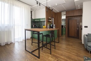 Una cocina moderna con una mesa de madera y taburetes de bar, un salpicadero verde y una puerta de madera.