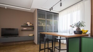 A modern kitchen with a wooden countertop, two black bar stools, a green cabinet, and a television on the left. - Cozy penthouse, terrace, artisan touch perfect espresso & perks (Belgrade)