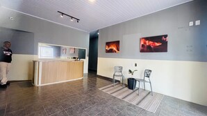 A reception area with a counter, two chairs, a potted plant, and artwork on the walls.