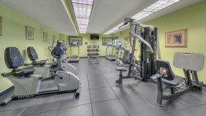 Ein Fitnessraum mit Laufbändern, Krafttrainingsgeräten und einer Spiegelwand.