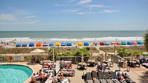 Ein Strandresort mit Pool, Liegestühlen und Sonnenschirmen.