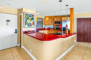A kitchen with a red island, wooden cabinets, a microwave, and a toaster. - Oceanfront Hale Hui Kai 313 Large Lanai, AC, Incredible Views on Keawakapu Beach (Kihei)