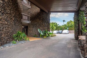 Un edificio de piedra con un porche cubierto y un camino de entrada pavimentado.