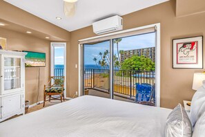 A hotel room with a large bed, a television, a chair, and a balcony with a view of the beach and ocean. - Oceanfront Hale Hui Kai 313 Large Lanai, AC, Incredible Views on Keawakapu Beach (Kihei)