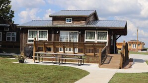 A wooden building with a covered picnic area, outdoor seating, and a small deck.
