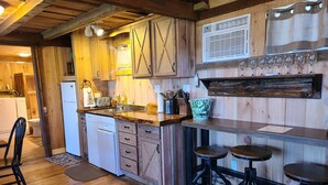 A kitchen with wooden cabinets, a dishwasher, and a bar area with stools.